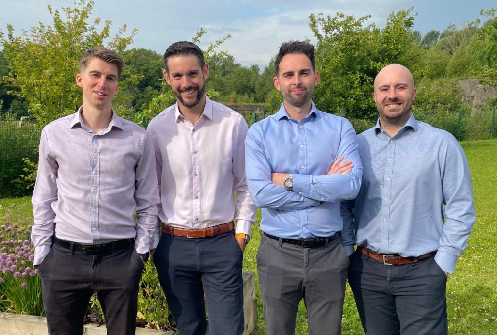 Image shows four men standing outside